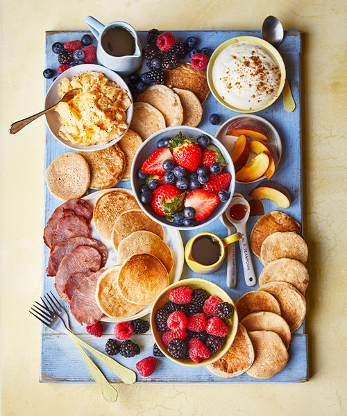 Slimming World pancake platter with pancakes, bacon, scrambled egg, fruit, yogurt and syrup